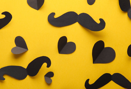 Paper mustache with black hearts on yellow background. Valentine's Day, love concept