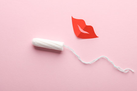 Feminine hygiene. Tampon with paper lips on a pink background. flat layの写真素材