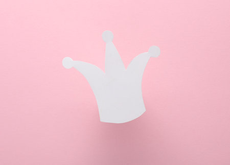 Paper-cut silhouette of a white crown on pink background.の写真素材