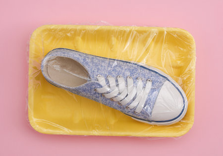 Retro Sneaker in a package wrapped with cellophane film on pink background. creative ideas. minimal...