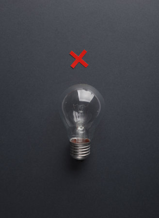 Incandescent light bulb with a rejection sign on a dark backgroundの写真素材
