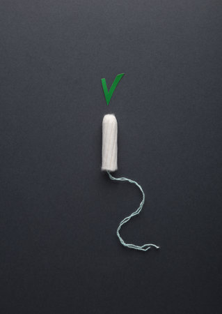 Tampon with acceptance checkmark on dark background. Women's intimate hygieneの写真素材