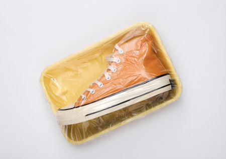 Retro Sneaker in a package wrapped with cellophane film on white background. creative ideas. minimal layoutの写真素材