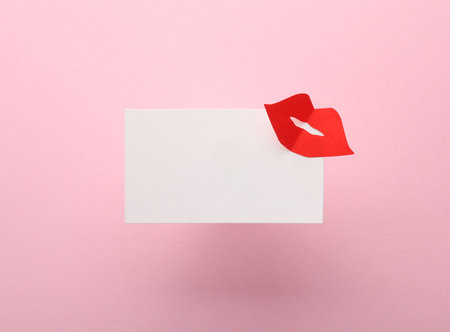 Business card with a paper kiss on a pink backgroundの写真素材