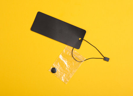 Black blank clothing price tag or label mockup with string on yellow background. sale, shopping...