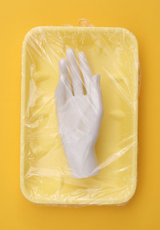Mannequin hand in package wrapped with cellophane film on a yellow background. creative ideas....