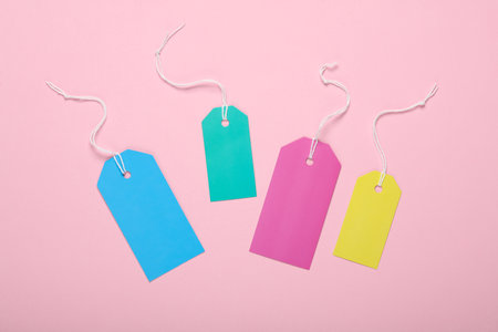 Colored Blank clothing price tags or labels mockup with strings on pink background. Sale, shopping concept. top viewの写真素材