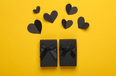 Black Friday. Valentine's Day. Black gift boxes with hearts on a yellow backgroundの写真素材