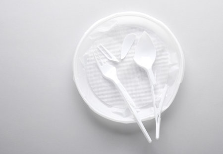 Broken plastic plate, fork and spoon on a gray background. Stop plastic pollution, recycling, eco conceptの写真素材