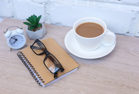 coffee break. Coffee cup with notebook on table against background of white brick wallの写真素材