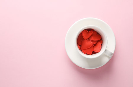 Ceramic coffee cup with red hearts on pink blue background. love concept. top viewの写真素材