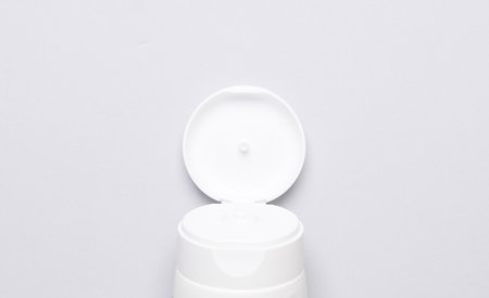 Open cream tube part on gray background. top view