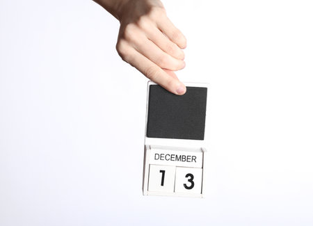 Female hand holding wooden calendar with date december 13 isolated on white backgroundの写真素材