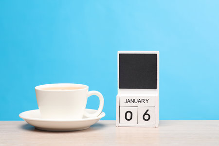 White wooden block monthly calendar with the date january 06 and coffee cup on the table, blue background. Planning, deadlineの写真素材