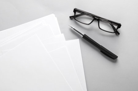 White blank sheets of a4 paper size or documents mockup with pen and eyeglasses on a gray background. Template for designの写真素材