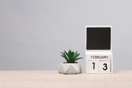 White wooden block monthly calendar with the date february 13 and plant on the table, gray background. Planning, business conceptの写真素材