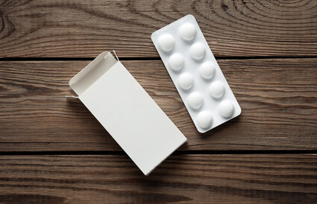 Pill blister mockup with blank cardboard box packaging on wooden table. Template for designの写真素材