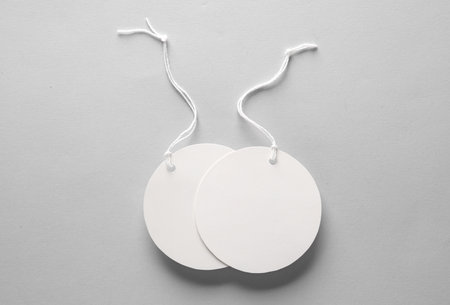 Round empty white price tags with string on gray background. Template for designの写真素材