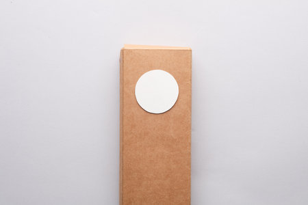 Kraft box with a white round label on a gray background. Template for designの写真素材
