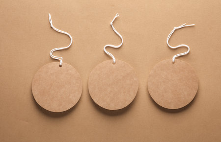 Empty round craft paper price tags with string on brown background. Template for designの写真素材