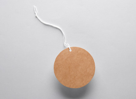 Empty round craft price tag with string on gray background. Template for designの写真素材