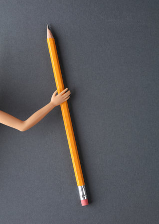 mannequin hand holding a pencil on gray background.の写真素材