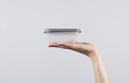 Plastic empty plastic bowl on a female palm, gray backgroundの写真素材