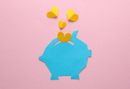 Paper-cut piggy bank with hearts on a pink background. Business, love concept, creative layoutの写真素材