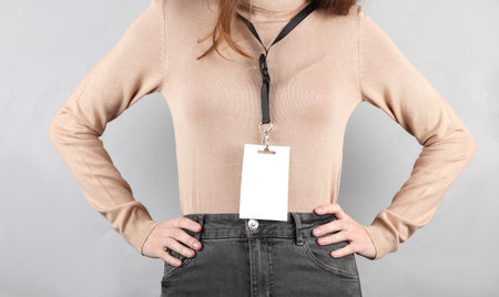 Young woman with Identification white blank id card on gray backgroundの写真素材