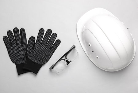 Protective equipment of a builder or engineer. Safety goggles, helmet and gloves on a gray background. top viewの写真素材