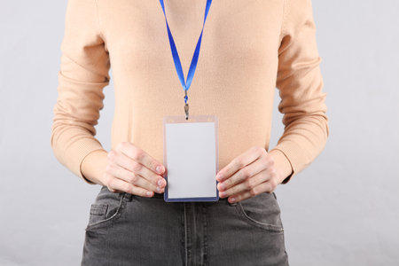 Young woman wearing Identification white blank id card on gray backgroundの写真素材