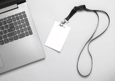 Laptop and Empty white ID card badge mockup on gray background. Staff identity name tag. Space for text and design.の写真素材