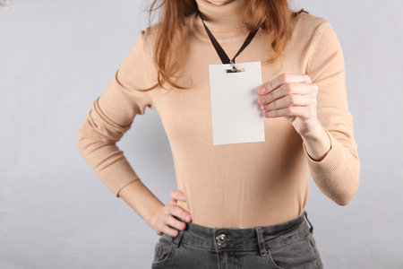 Young woman wearing Identification white blank id card on gray backgroundの写真素材
