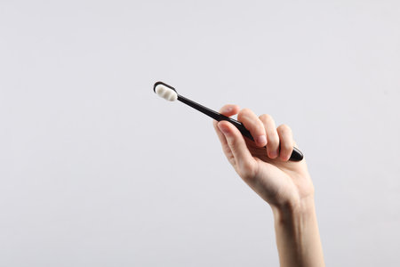 Woman's hand holds black toothbrush on a gray background. caring for teeth conceptの写真素材