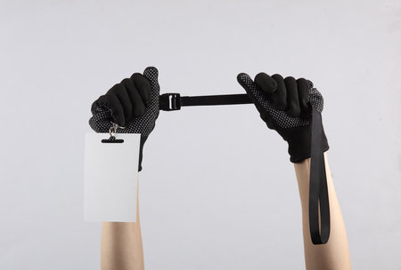 Female hand in working fabric glove holding Identification white blank id cards on gray backgroundの写真素材