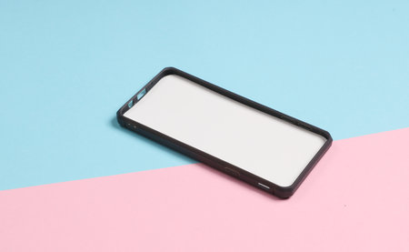 Black silicone case for a smartphone with a white tab on pink blue backgroundの写真素材