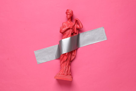Antique statue of venus fixed with adhesive tape on a pink background. Conceptual pop, contemporary art, minimalist still lifeの写真素材