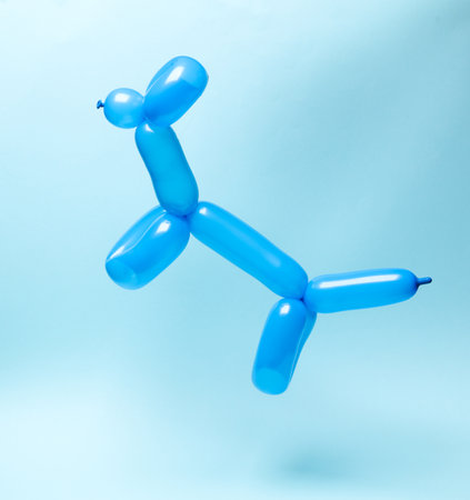 Blue balloon in the shape of dog levitating on blue background.の写真素材