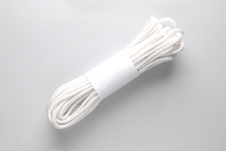 Woman's hand holds a coil of rope levitating on gray background