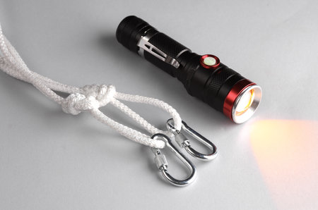 Rope with knots, loops, carabiners and flashlight on gray background. Climbing equipmentの写真素材