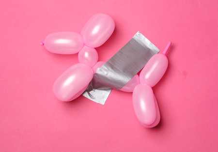 Balloon dog fixed with adhesive tape on a pink background. Conceptual pop, contemporary art, minimalist still lifeの写真素材