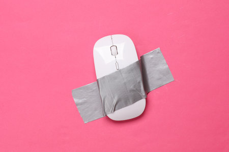 PC mouse fixed with adhesive tape on a pink background. Conceptual pop, contemporary art, minimalist still lifeの写真素材