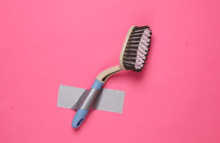 Cleaning brush fixed with adhesive tape on a pink background. Conceptual pop, contemporary art, minimalist still lifeの写真素材