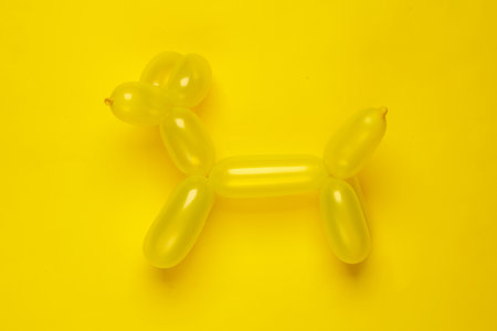 Yellow balloon in the shape of a dog on yellow background. top viewの写真素材