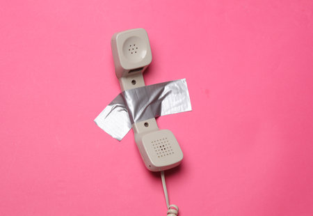 Retro phone tube fixed with adhesive tape on a pink background. Conceptual pop, contemporary art, minimalist still lifeの写真素材