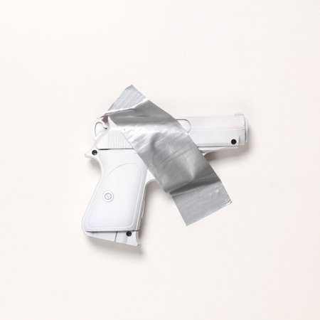 Plastic white gun fixed with adhesive tape on white background. Conceptual pop, contemporary art, minimalist still life. stop warの写真素材