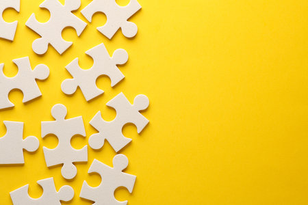 White jigsaw puzzle pieces on yellow background.の写真素材