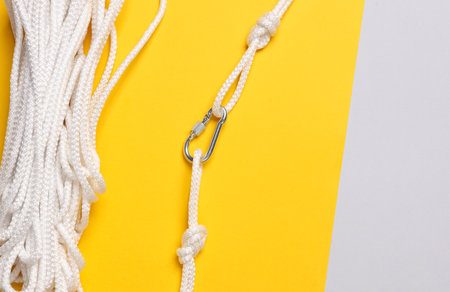 Climbing rope with a carabiner on a yellow background