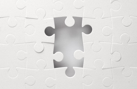 White jigsaw puzzle pieces on a gray background.の写真素材