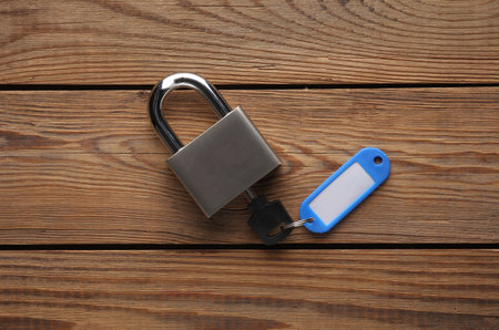 Plastic tag with metal key and lock on wooden table